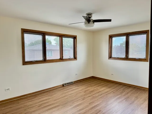 a view of empty room with wooden floor and fan