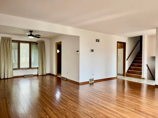 a view of an empty room with wooden floor and stairs