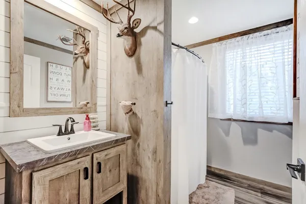 a bathroom with a granite countertop sink a mirror and a shower