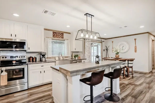 a kitchen with stainless steel appliances a stove center island cabinets and wooden floor