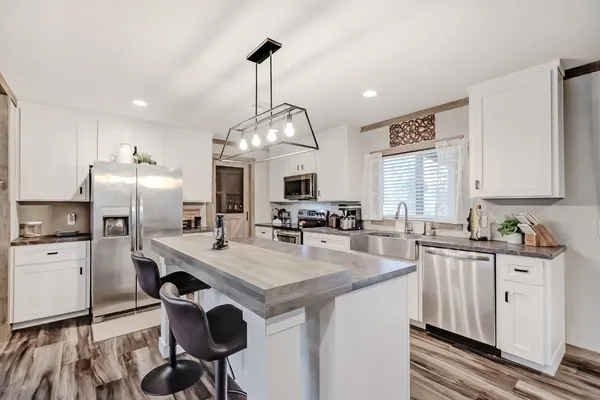 a kitchen with kitchen island granite countertop a sink appliances and cabinets