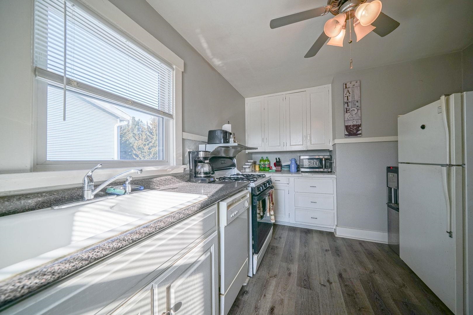 409 West Lincoln Street Mount Morris, IL 61054 - Photo 6 of 28 a kitchen with a sink dishwasher a refrigerator a stove and white cabinets with wooden floor