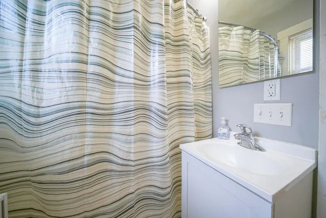 a bathroom with a sink a mirror and shower curtain