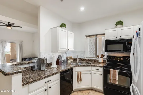 a kitchen with granite countertop a sink stainless steel appliances and white cabinets