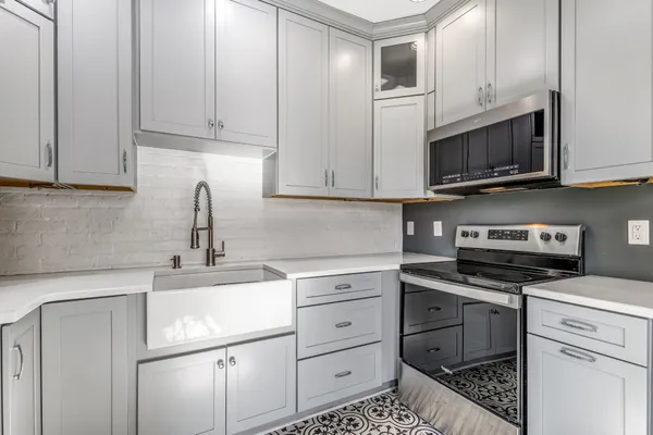 a kitchen with stainless steel appliances a sink a stove a refrigerator cabinets and dining table