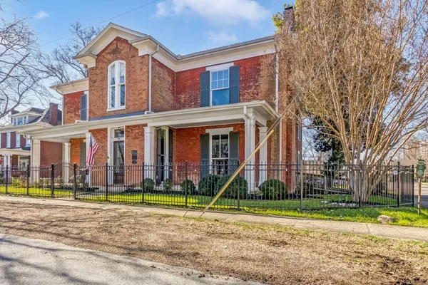a view of a big house with a yard and plants