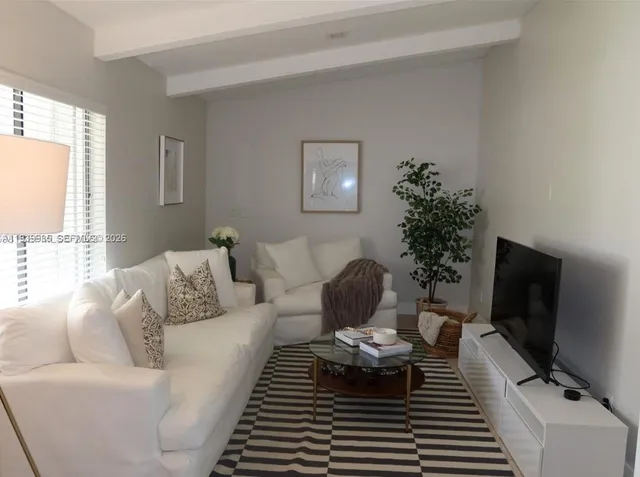 a living room with furniture a flat screen tv and a large window