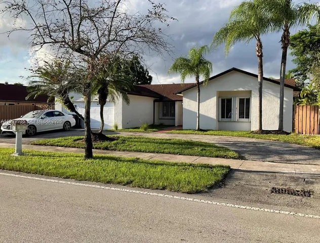 a front view of a house with a garden and trees