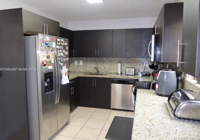 a kitchen with granite countertop a refrigerator and a sink