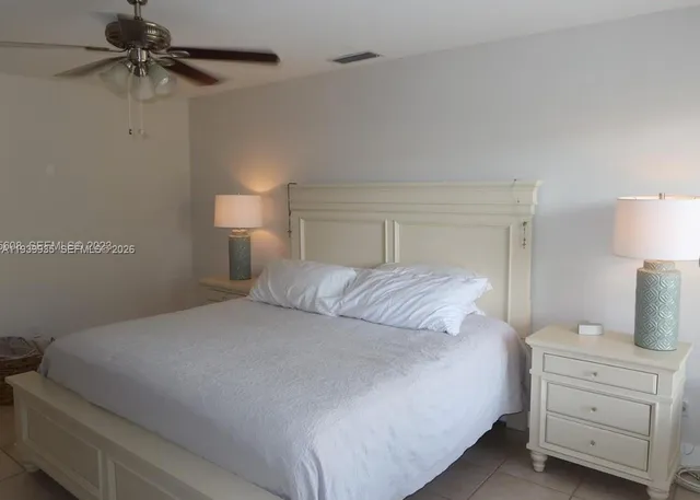 a bedroom with a bed and a lamp on the dresser