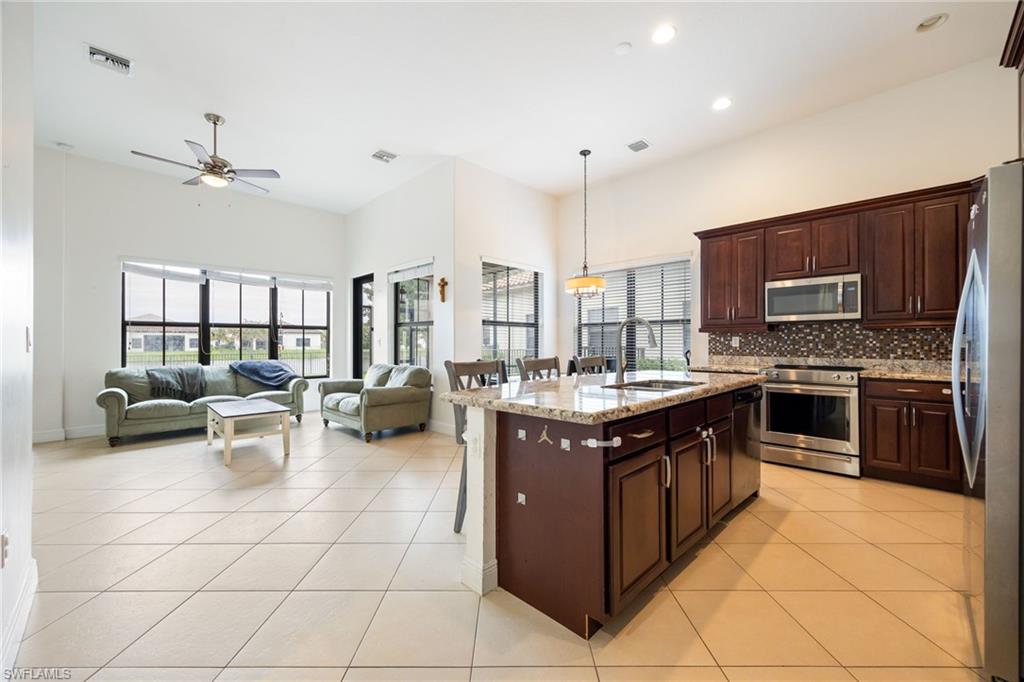 5116 Salerno Street Ave Maria, FL 34142 - Photo 35 of 36 Kitchen with a breakfast bar area, stainless steel appliances, light stone counters, open floor plan, and an island with sink