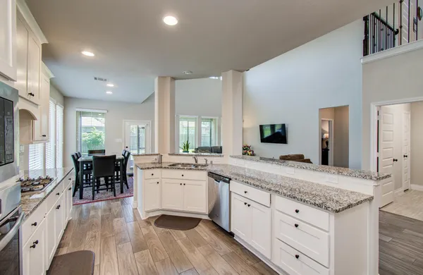 a kitchen with granite countertop white cabinets and stainless steel appliances