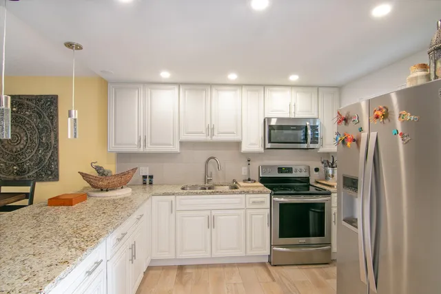 a kitchen with stainless steel appliances granite countertop a sink stove and refrigerator