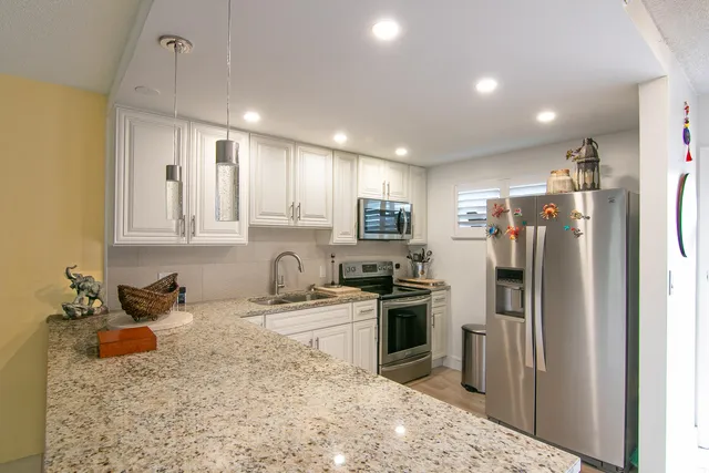a kitchen with stainless steel appliances granite countertop a sink stove and refrigerator