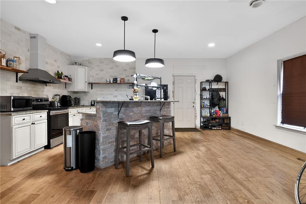 843 Fox Street Northwest Atlanta, GA 30318 - Photo 8 of 30 a kitchen with stainless steel appliances granite countertop a stove a refrigerator a kitchen island a dining table and chairs with wooden floor