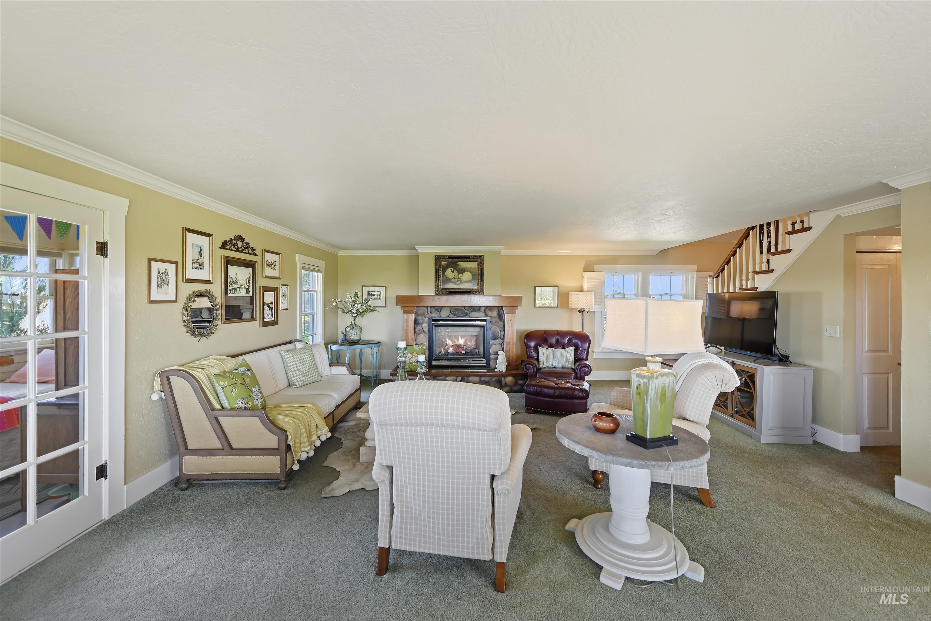 19234 Top Road Caldwell, ID 83607 - Photo 11 of 50 Living room featuring crown molding, stairs, carpet floors, healthy amount of natural light, and a fireplace