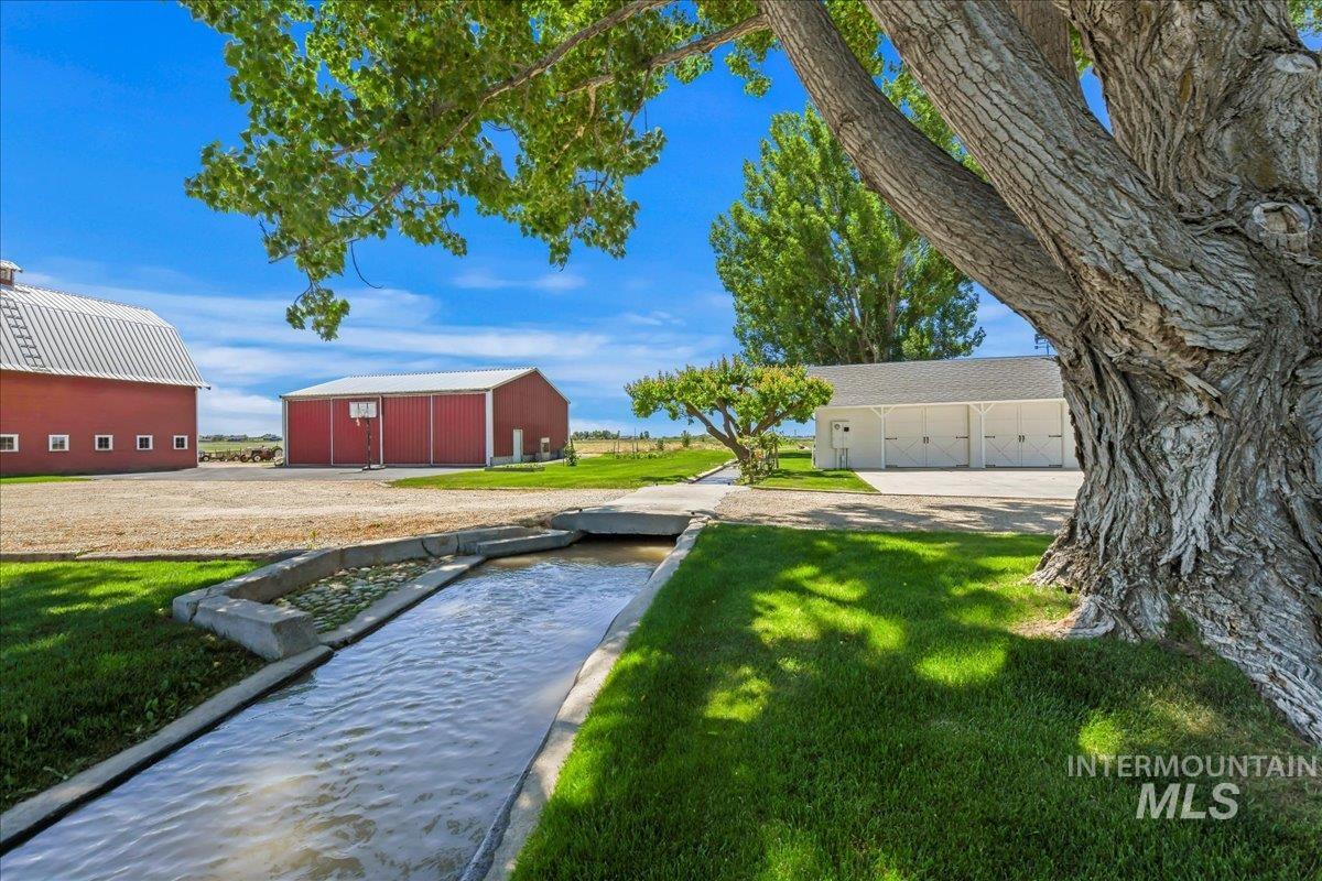 19234 Top Road Caldwell, ID 83607 - Photo 27 of 50 View of green lawn featuring an outdoor structure, a pole building, a detached garage, and a garden pond
