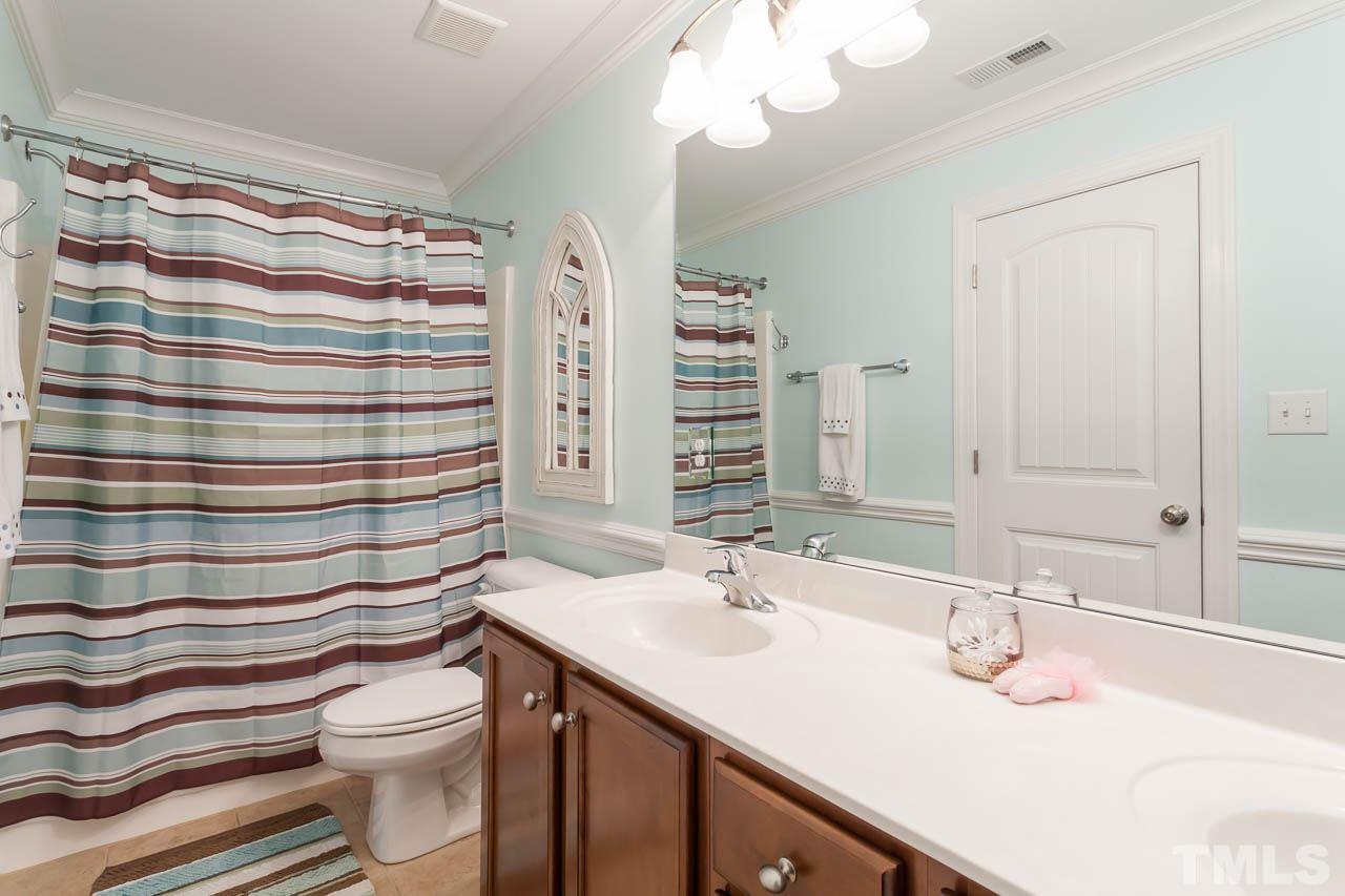 1014 Vino Drive Raleigh, NC 27607 - Photo 23 of 25 a bathroom with a sink a toilet a large mirror and shower curtain