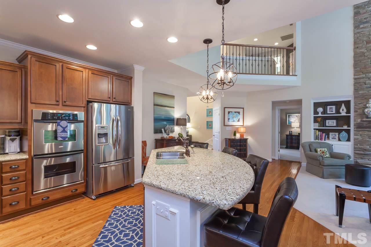 1014 Vino Drive Raleigh, NC 27607 - Photo 10 of 25 a kitchen with stainless steel appliances granite countertop a refrigerator a sink dishwasher a dining table and chairs with wooden floor