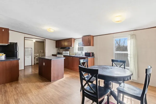 a kitchen with stainless steel appliances granite countertop a sink dishwasher stove and wooden cabinets with wooden floor