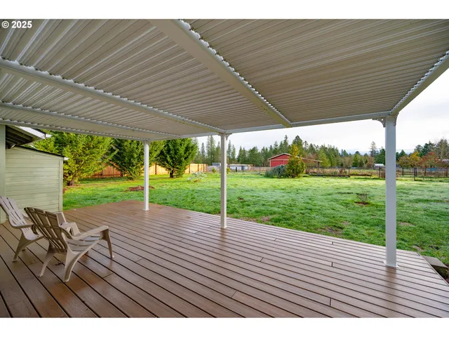 a view of a yard in front of a house with plants and large tree