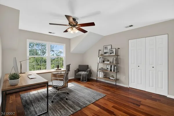 a view of empty room with wooden floor and fan