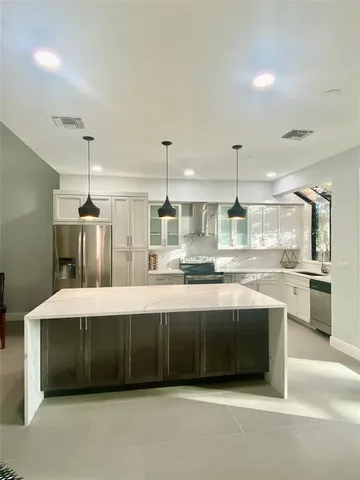 a large kitchen with kitchen island a stove a sink a refrigerator and white cabinets
