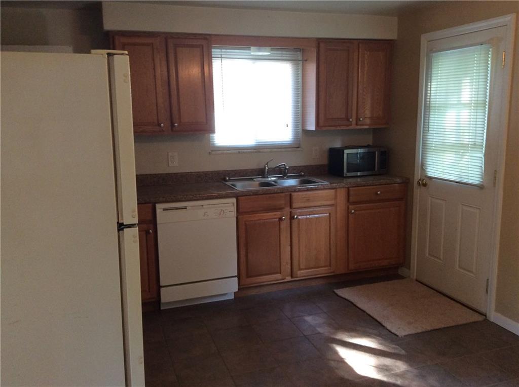 Kitchen with ceramic tile floor. Refrigerator, dishwasher and microwave included (as-is). Door to backyard.