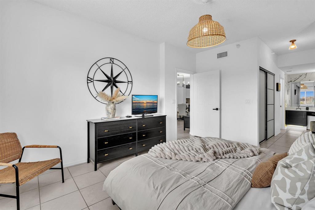 7775 Southampton Terrace, Unit 405 Tamarac, FL 33321 - Photo 29 of 82 a bedroom with a bed and a chandelier