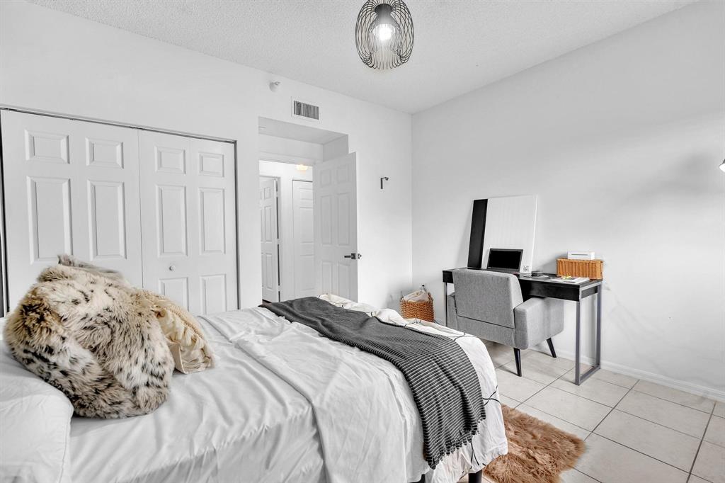 7775 Southampton Terrace, Unit 405 Tamarac, FL 33321 - Photo 39 of 82 a bedroom with a bed and a chandelier