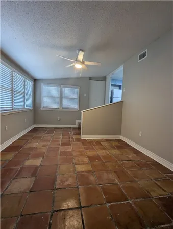 a view of an empty room with window and chandelier fan