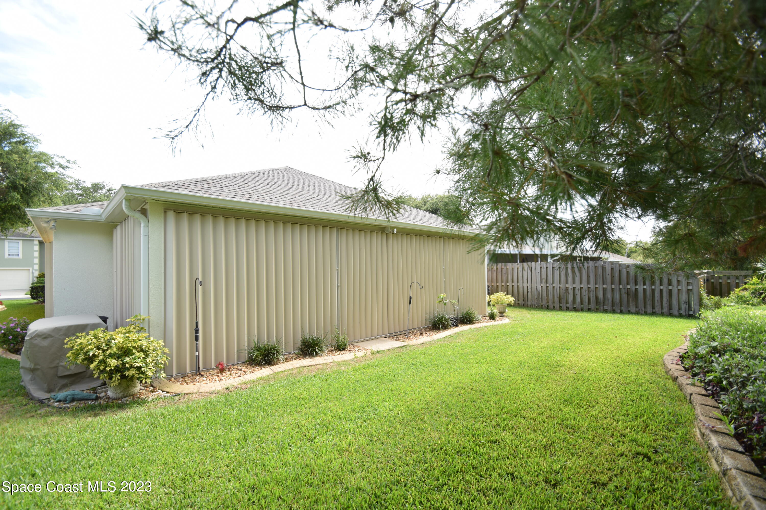 2190 Spring Creek Circle Palm Bay, FL 32905 - Photo 49 of 73 a backyard of a house with potted plants and large tree