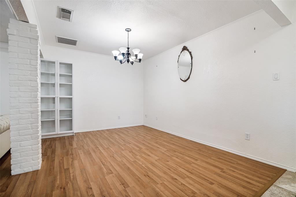 7706 Swiss Way Rowlett, TX 75089 - Photo 4 of 21 Dedicated dining space with updated flooring, elegant lighting, and a bookcase for added character as well as functionality.