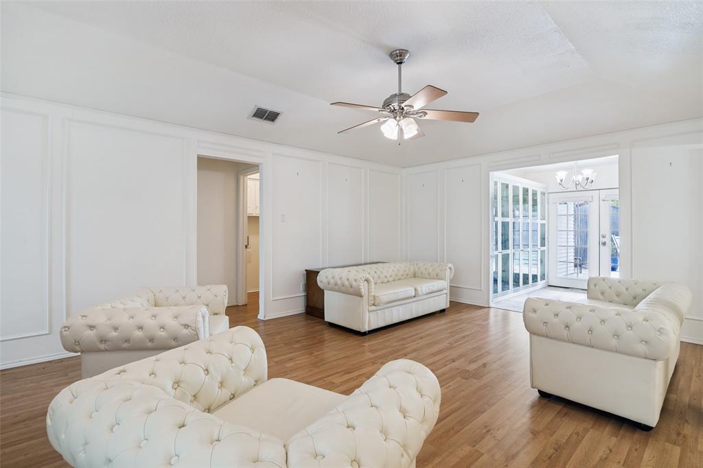 7706 Swiss Way Rowlett, TX 75089 - Photo 5 of 21 Spacious living area featuring a decorative wall, ceiling fan, wood finished floors, and suspended lighting.