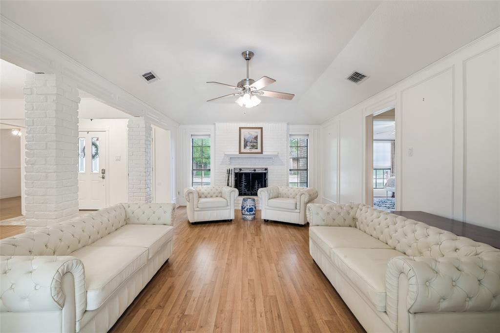 7706 Swiss Way Rowlett, TX 75089 - Photo 6 of 21 Open-concept living room centered around a cozy fireplace with large windows.