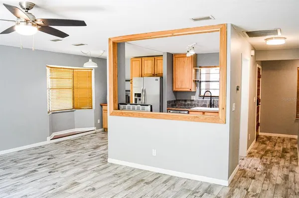 a living room with stainless steel appliances wooden floor and a chandelier
