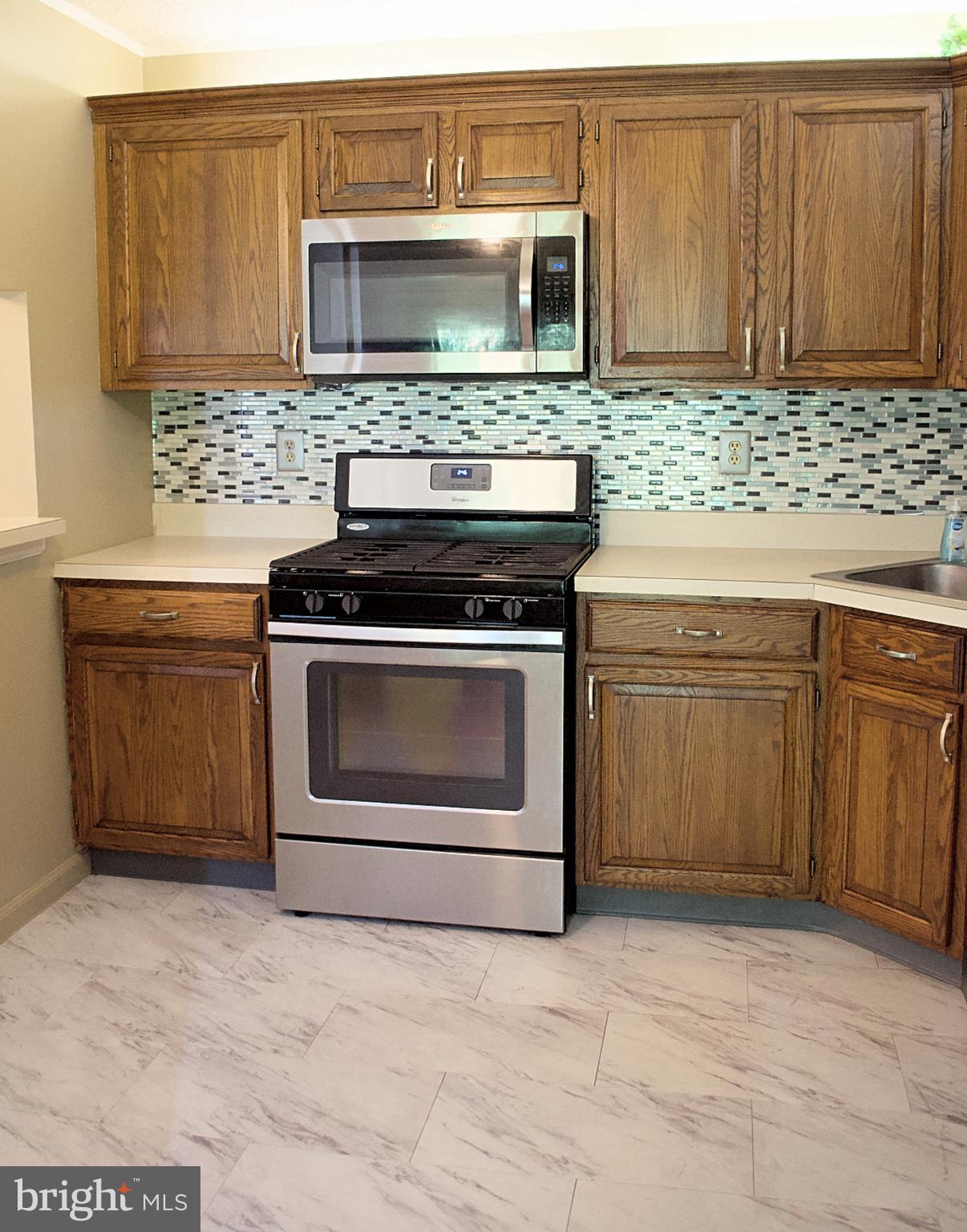 84 Willow Court Hamilton, NJ 08619 - Photo 5 of 18 a kitchen with granite countertop a stove top oven microwave and cabinets