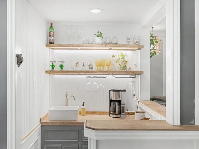 a view of white kitchen with a sink and wooden floor