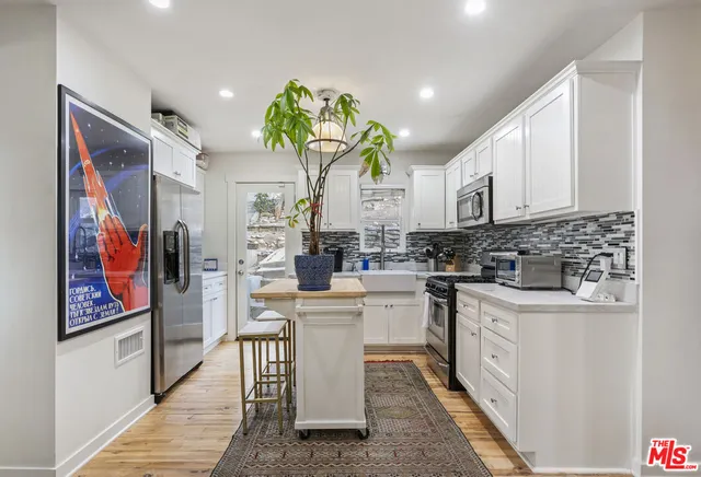 a kitchen with stainless steel appliances granite countertop a refrigerator a sink dishwasher and white cabinets with wooden floor