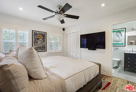 a bedroom with a large bed a flat tv screen and a dresser