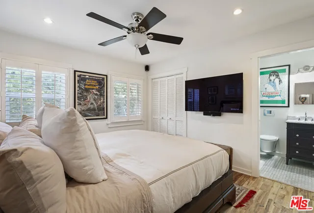 a bedroom with a large bed a flat tv screen and a dresser