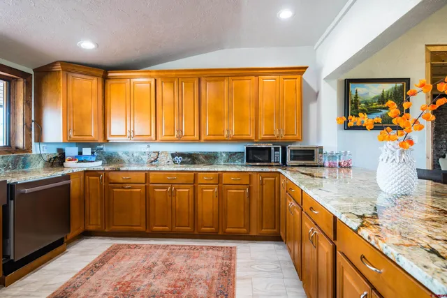 a kitchen with stainless steel appliances granite countertop wooden cabinets a granite counter top and a sink