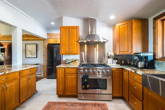 a kitchen with stainless steel appliances granite countertop a stove a sink and a refrigerator