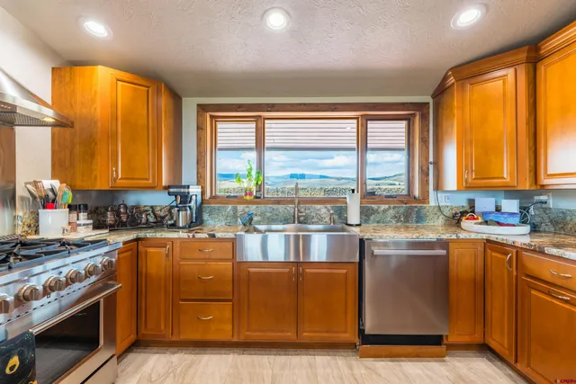 a kitchen with stainless steel appliances granite countertop sink stove and wooden cabinets