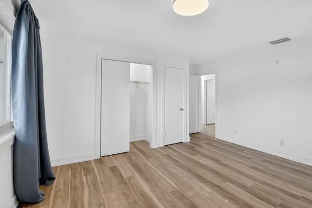 a view of an empty room with wooden floor and a window