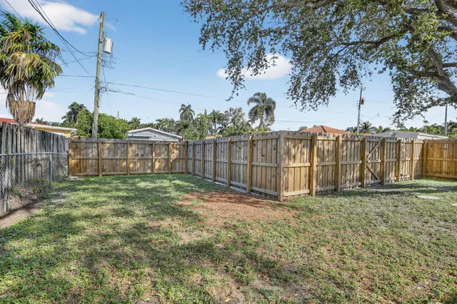 a view of a backyard with large trees and wooden fence