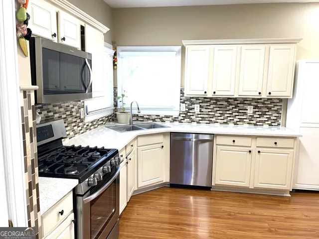 a kitchen with stainless steel appliances granite countertop a stove a sink and a microwave