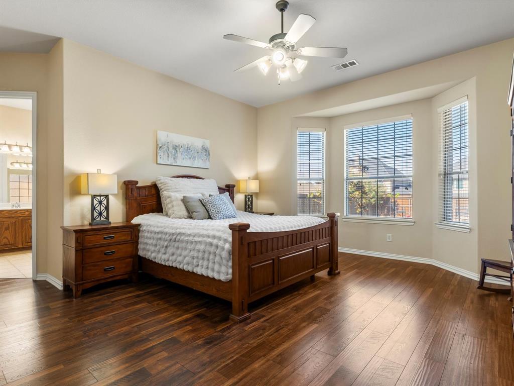 5365 Royal Lytham Road Fort Worth, TX 76244 - Photo 14 of 37 a bedroom with a large bed a chandelier and windows