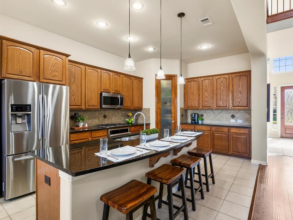 5365 Royal Lytham Road Fort Worth, TX 76244 - Photo 7 of 37 a kitchen with stainless steel appliances granite countertop a refrigerator a stove a sink a dining table and chairs