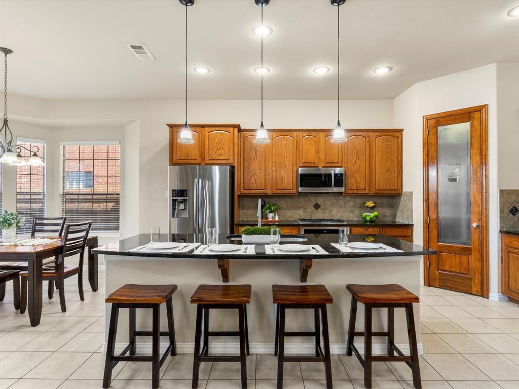 5365 Royal Lytham Road Fort Worth, TX 76244 - Photo 8 of 37 a kitchen with stainless steel appliances kitchen island granite countertop a table chairs sink and window